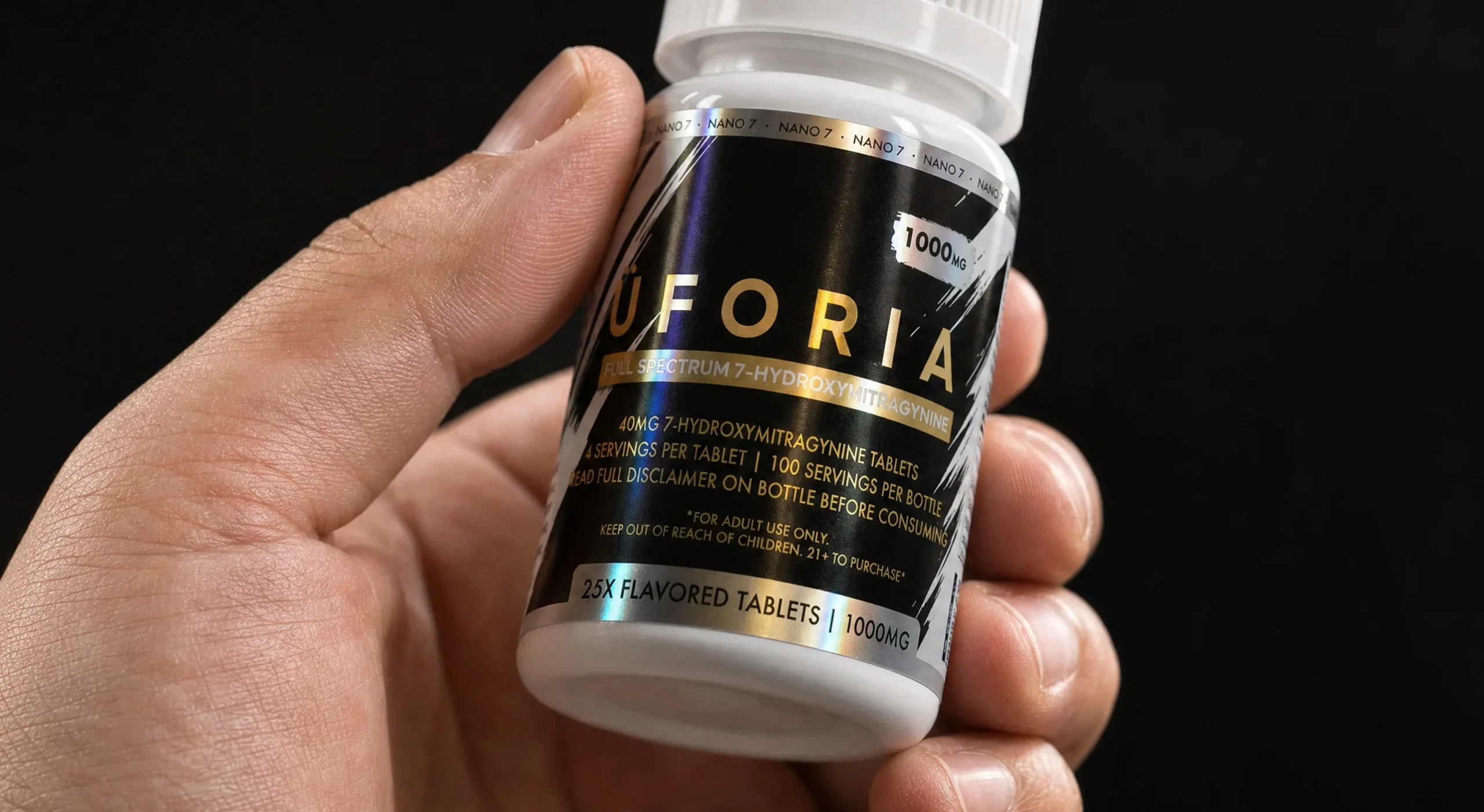 Bote de Uforia en negro con acabados en foil dorado y holográfico, sostenido en mano