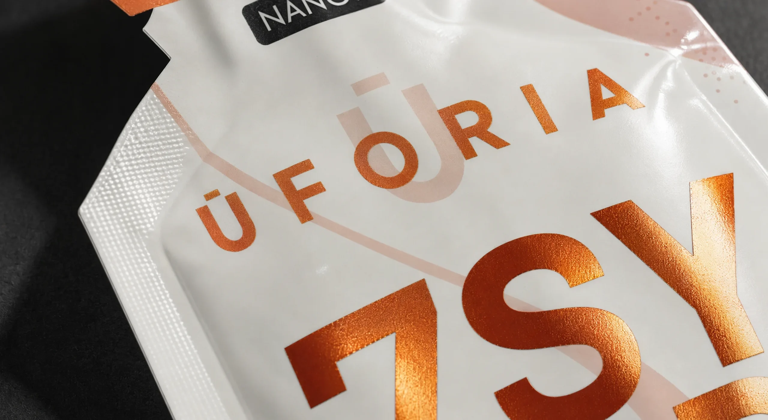 Detalle de sachet de Uforia, tipografía en foil cobre sobre laminado blanco mate