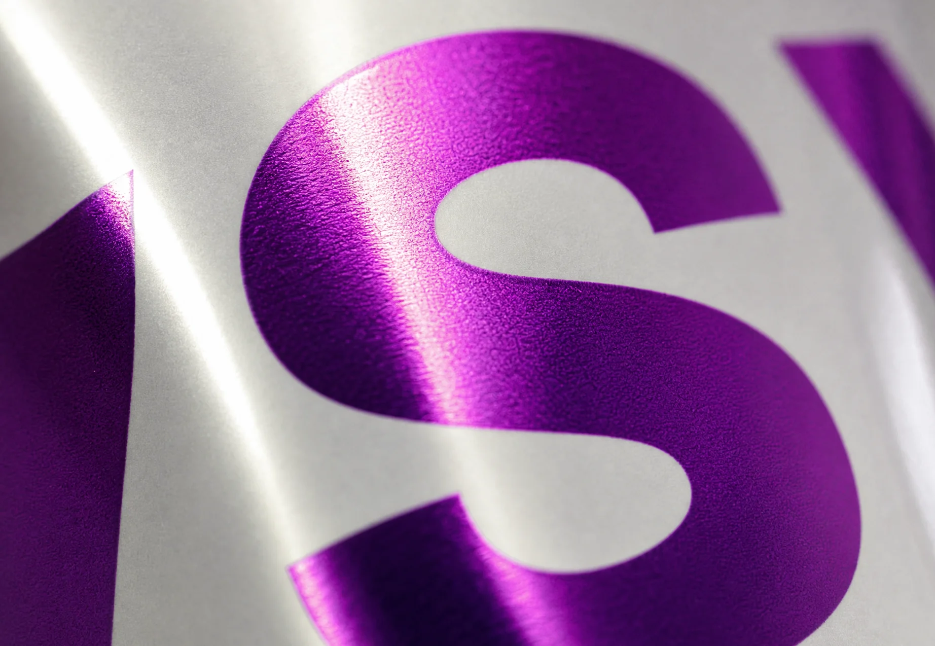Detalle de estampación en foil violeta metalizado sobre soporte plateado