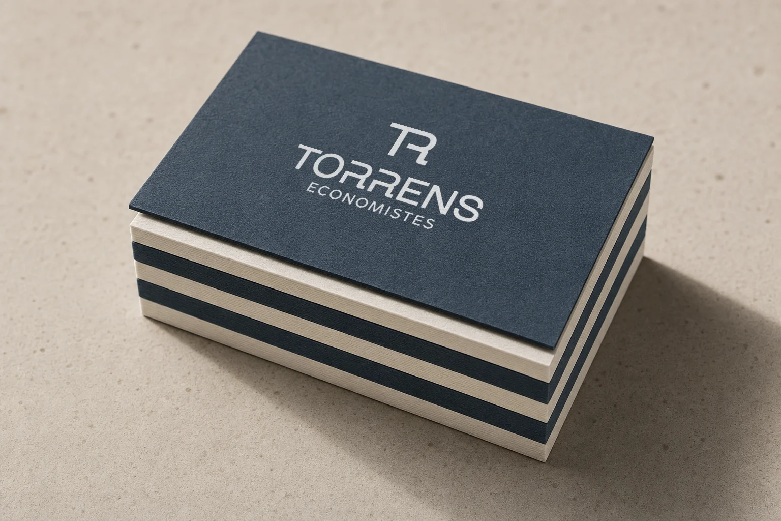 Tarjetas de Torrens Economistes apiladas, alternando cartulina azul y crema con logotipo en blanco